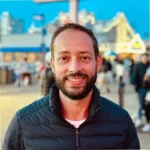 Eduardo Quintiliano coordenador do Templo e instrutor sobre IA homem branco de cabelos e barba castanha usa jaqueta de frio preta com blusa sem gola branca